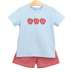 Children's light blue t-shirt with red and green checkered apples and red gingham shorts on a white background.