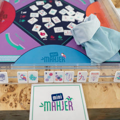 Mini Mahjong game set with tiles and packaging on a wooden surface