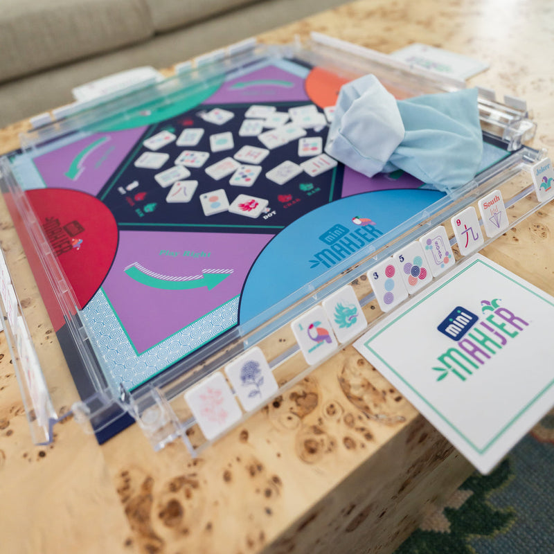 Close-up of a Mahjong game set with tiles and board on a wooden surface.