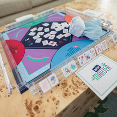 Close-up of a Mahjong game set with tiles and board on a wooden surface.